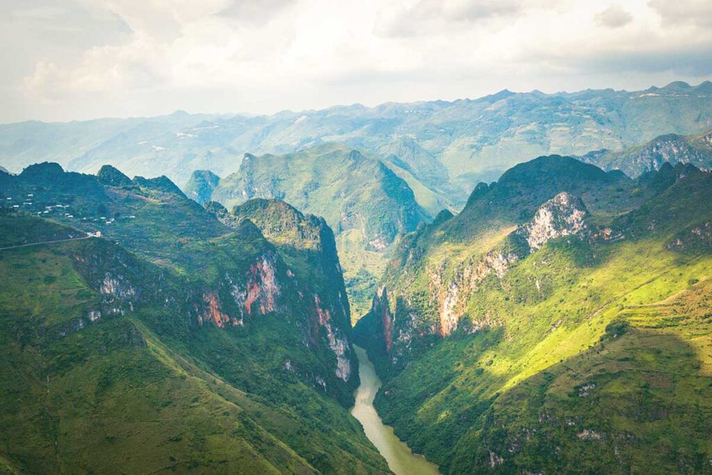 A breathtaking panorama from Ma Pi Leng Pass, with lush green mountains and the Nho Que River flowing far below.