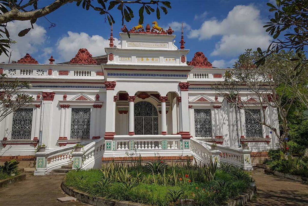 Colonial-era Huynh Ky Mansion in Tra Vinh with European-inspired architecture, red and white detailing, and a garden entrance.