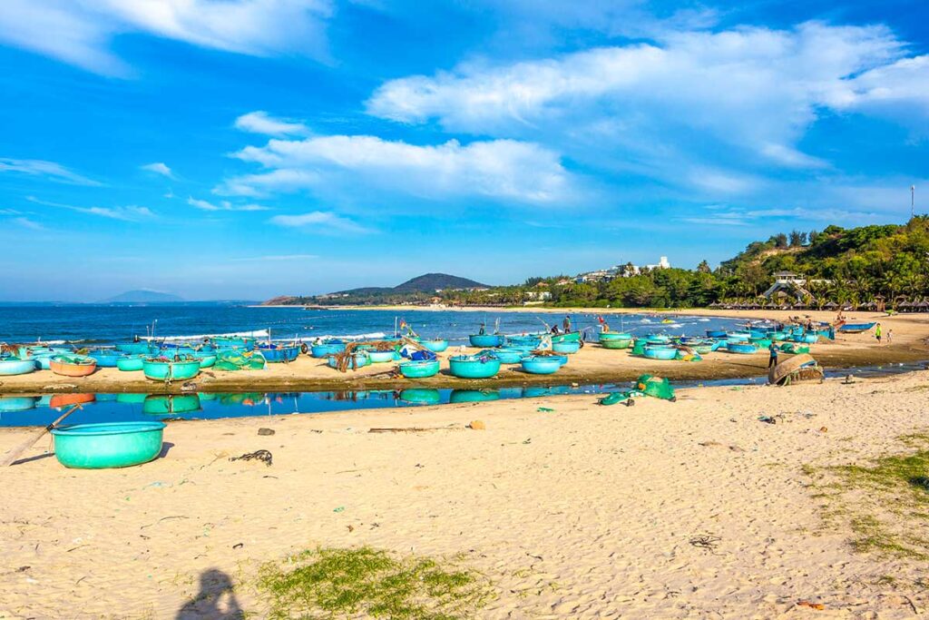 Mui Ne in May: A peaceful beach in Mui Ne in May, where traditional Vietnamese basket boats rest on the shore under sunny skies, reflecting the region’s fishing heritage.