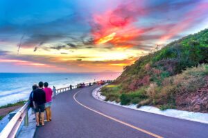 Mui Ne in November: A breathtaking Mui Ne sunset in November, with a clear sky and deep red-orange hues illuminating the coastal road, creating a perfect evening scene.