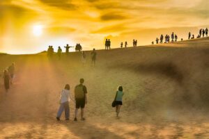 Mui Ne in December: The White Sand Dunes in Mui Ne in December, glowing under a golden sunset, as a crowd gathers on top to watch the sun set over the vast landscape.