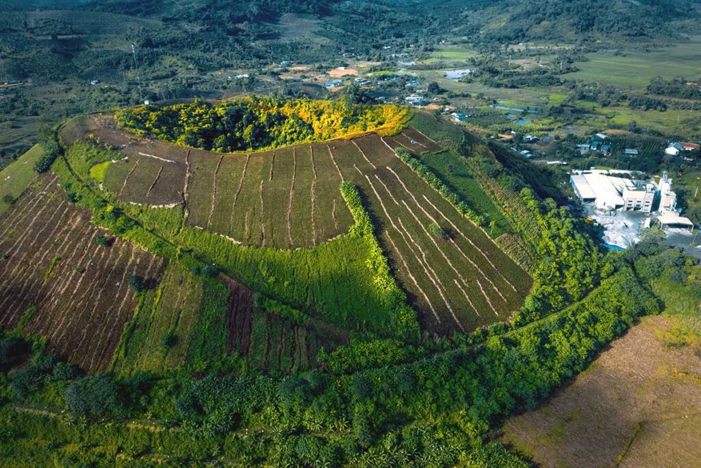 A stunning aerial shot of Nam Kar Volcano, showcasing its distinct crater and the surrounding lush landscape within Dak Nong Geopark.