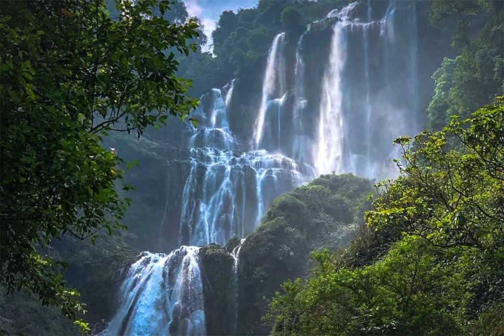 Nam Me Waterfall with water cascading down high of a cliff
