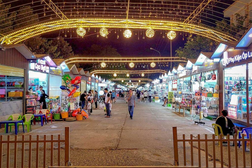 Ninh Thuan Tourist Night Market in Phan Rang, busy with shoppers browsing food stalls, souvenirs, and brightly lit shops.