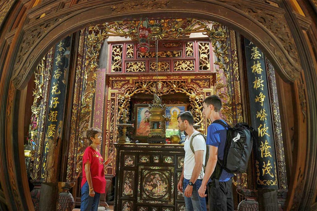 Visitors being shown the ornate ancestral altar decorated with gilded carvings and mother-of-pearl inlays inside Ong Kiet’s Ancient House in Cai Be, Tien Giang.