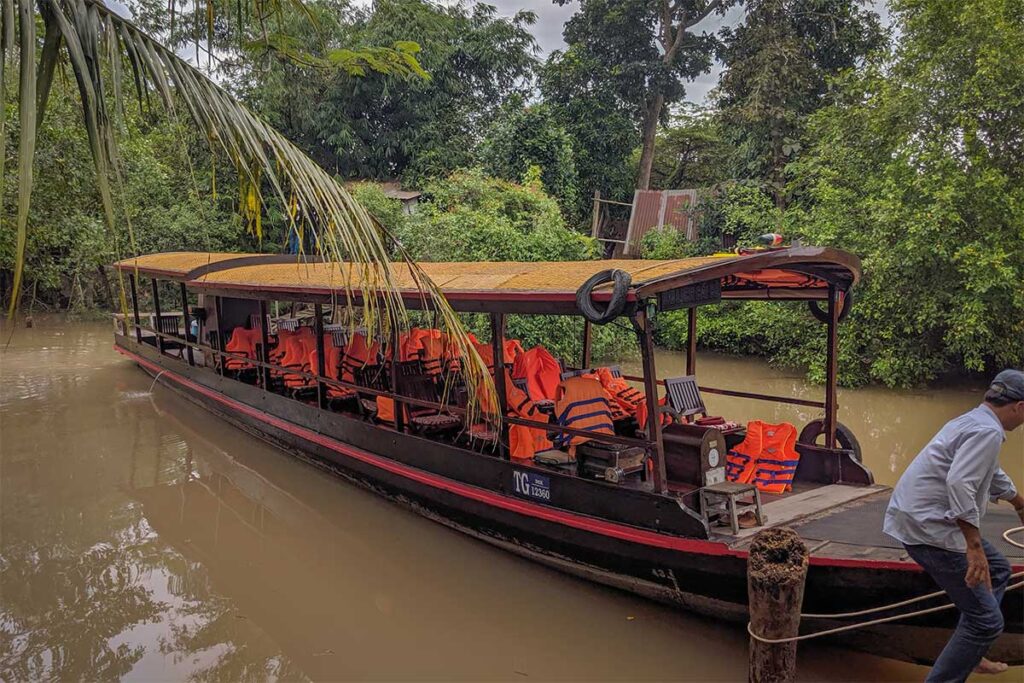 Traditional tour boat with life jackets ready for passengers on a canal in Cai Be, Tien Giang – a common way to combine a Mekong Delta boat tour with a visit to Ong Kiet’s Ancient House.