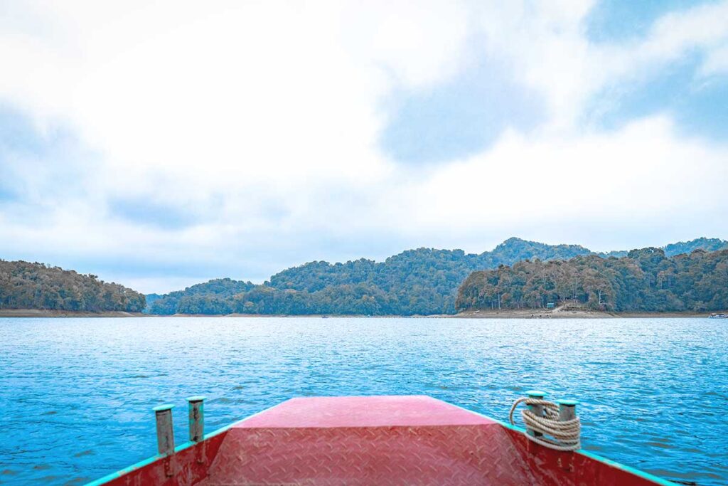 A peaceful view from a boat on Pa Khoang Lake, surrounded by calm waters and lush greenery.