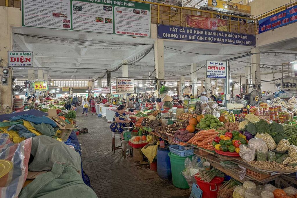 Phan Rang central market with colorful stalls of fresh vegetables, fruits, and local produce under a bustling roofed hall