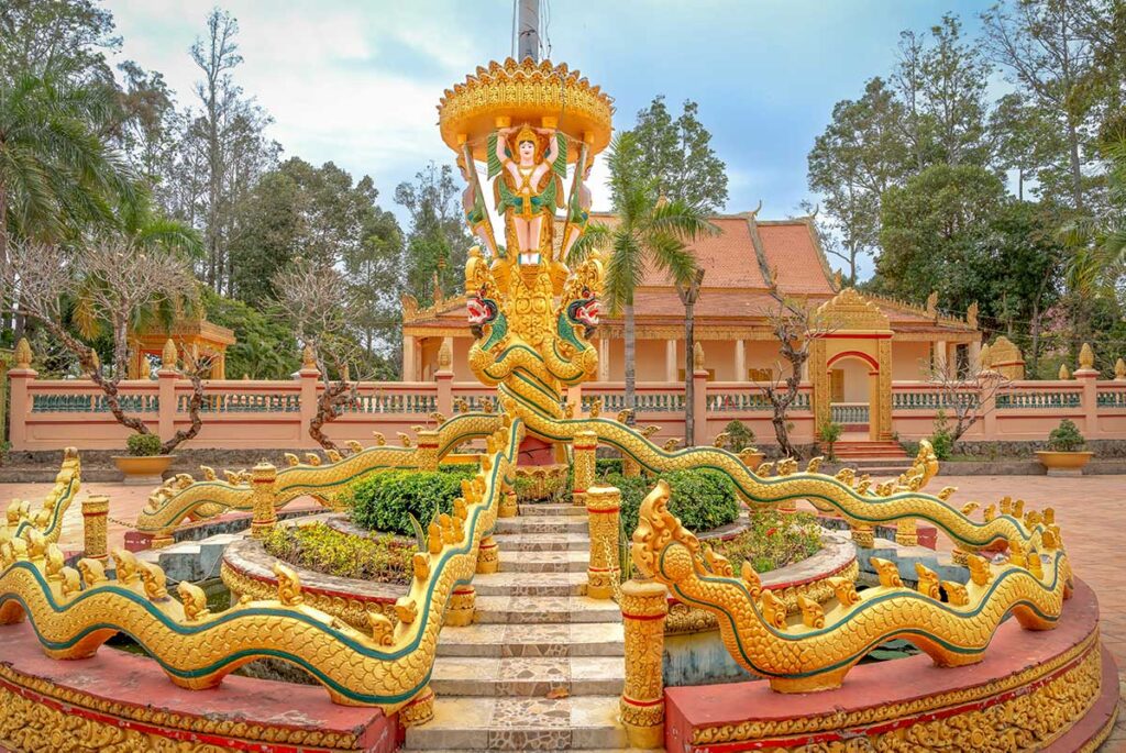 Decorative golden dragon fountain and religious statue in the courtyard of Phat Lon Pagoda, a Khmer temple in Rach Gia, Vietnam.