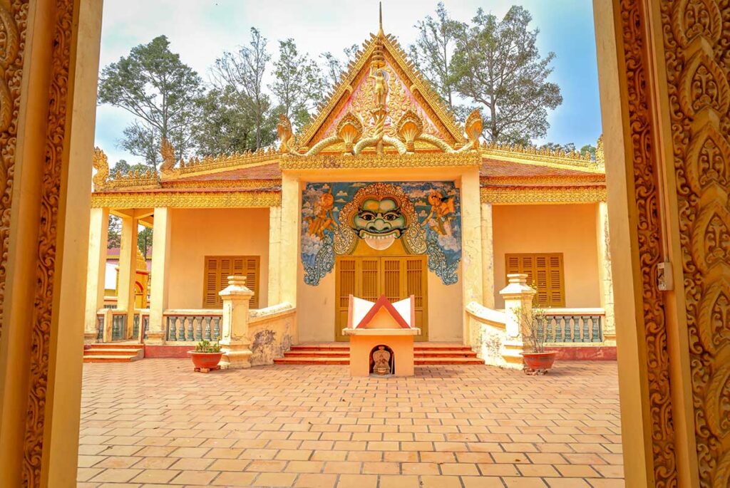 Entrance to Phat Lon Pagoda in Rach Gia, a Khmer-style Buddhist temple with intricate architecture and bright yellow-red tones reflecting Khmer heritage.