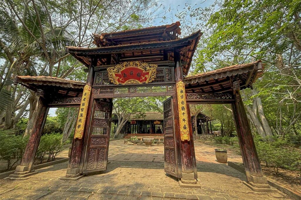 Ornate wooden gate of Phuoc Loc Tho Ancient Village in Long An Province, showcasing traditional Vietnamese architecture and calligraphy.