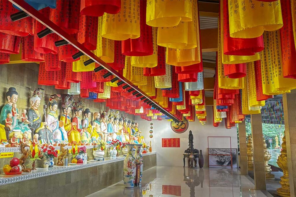 Interior of Quan Am Linh Ung Pagoda with rows of deity statues and colorful lanterns in Soc Trang.