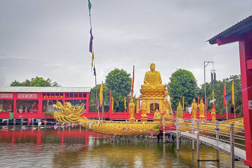 Colorful golden Buddha statue and dragon boat sculpture at Quan Am Linh Ung Pagoda in Soc Trang, Vietnam.