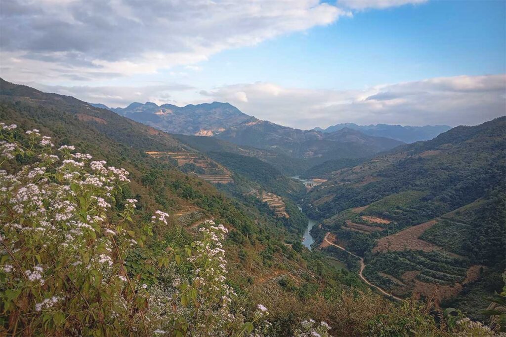 A stunning landscape of rugged mountains and a winding stream below, taken from the Tua Chua Karst Plateau.