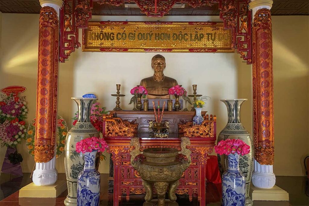 Uncle Ho Temple in Hau Giang Province, Vietnam – interior view with golden bust of Ho Chi Minh, incense altar, and decorated wooden carvings.