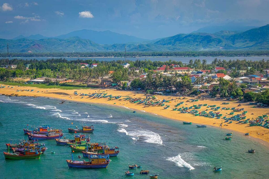 Fishing boats and round basket boats along the sandy shore of Xuan Hai fishing village beach in Phu Yen.