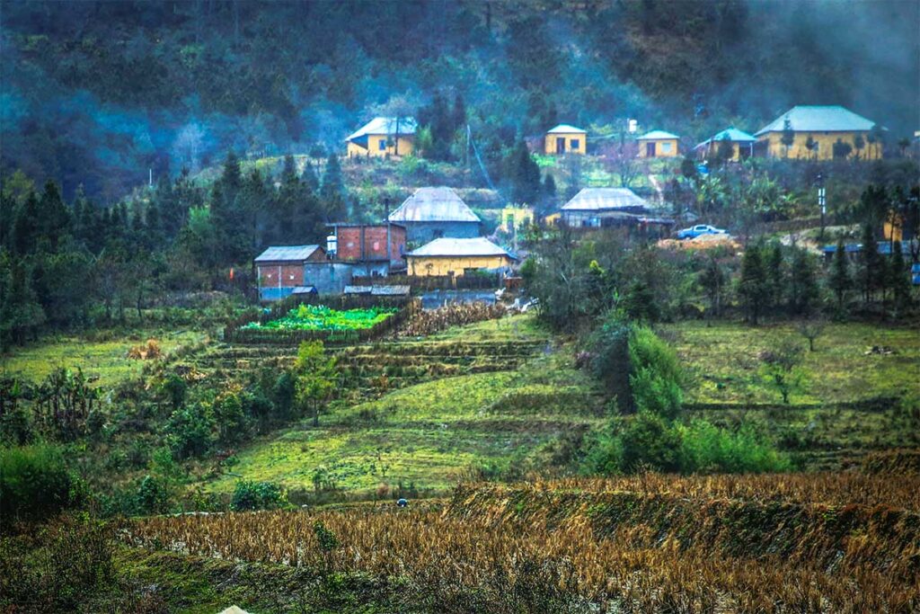 An ethnic village with traditional houses against a mountain in Y Ty Commune