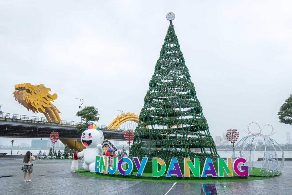 Da Nang in December – A festive scene with a large Christmas tree and decorations, with the iconic Dragon Bridge in the background.