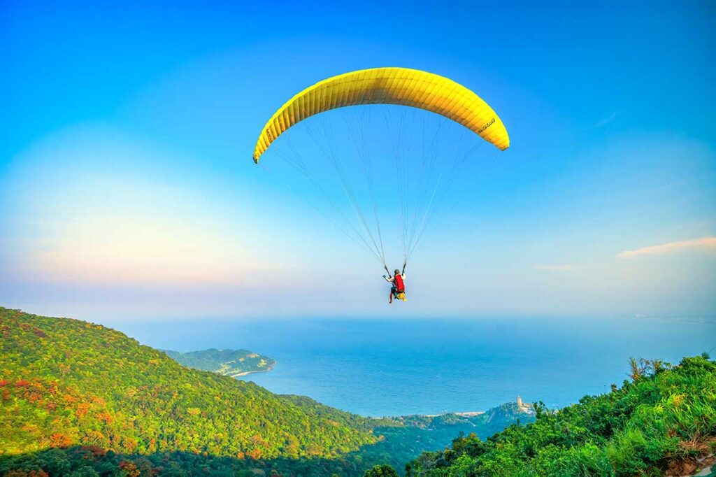 Da Nang in April – Tandem paragliding over Son Tra Peninsula, with a stunning sunset sky and panoramic views of the coastline.