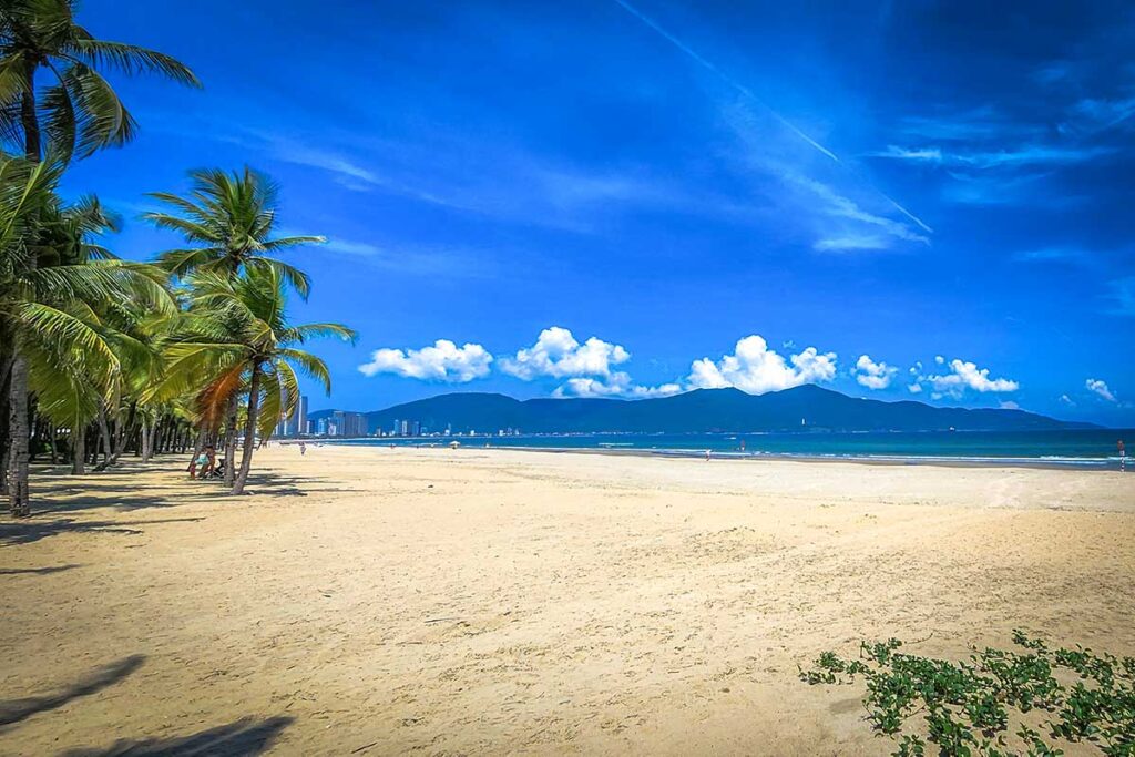 Da Nang in August – A quiet and peaceful My Khe Beach, with palm trees swaying and gentle waves rolling onto the shore.