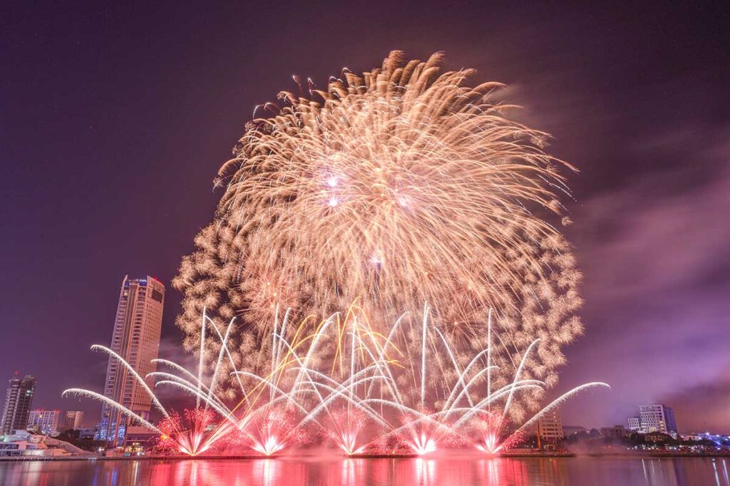 Spectacular fireworks display at the Da Nang International Fireworks Festival, viewed from the main stand with a clear night sky backdrop.