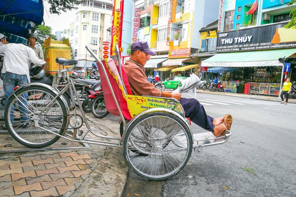 Da Nang in November – A cyclo driver passing by Han Market, capturing the lively atmosphere of Da Nang’s bustling streets.