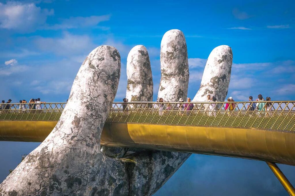 Da Nang in September – Tourists walking across the Golden Hand Bridge in Ba Na Hills, with good weather and a clear mountain view.