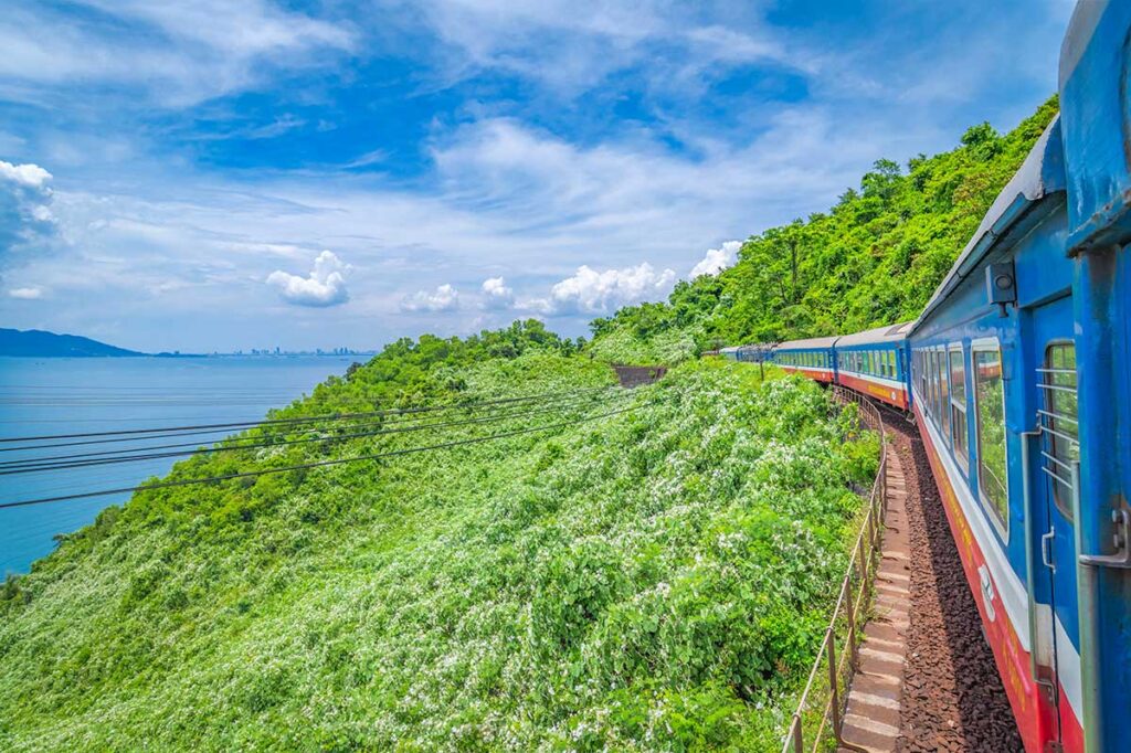 A view from the train window on the Hai Van Pass, capturing the train curving along the track with mountains on one side and the coastline on the other.