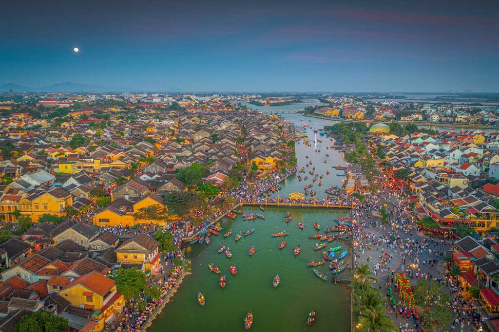 Aerial view of Hoi An Ancient Town at dusk with lanterns and boats on the Thu Bon River — showing the vibrant atmosphere that makes the dry season the best time to visit Hoi An.