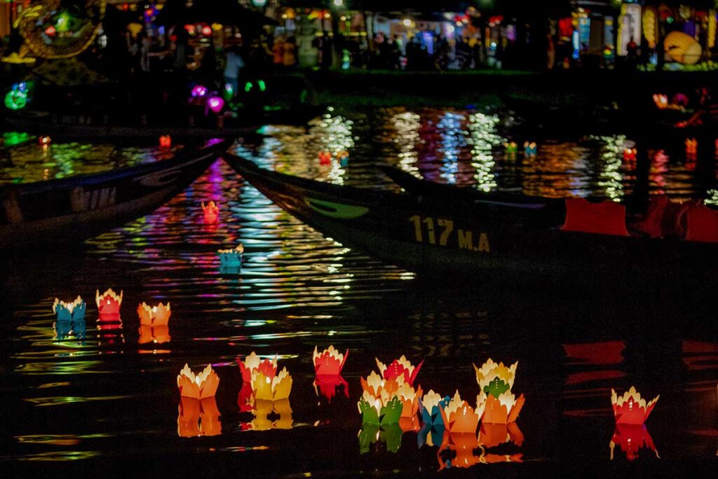 Floating paper lanterns on the Thu Bon River during the Hoi An Lantern Festival, reflecting colorful lights on the water at night.