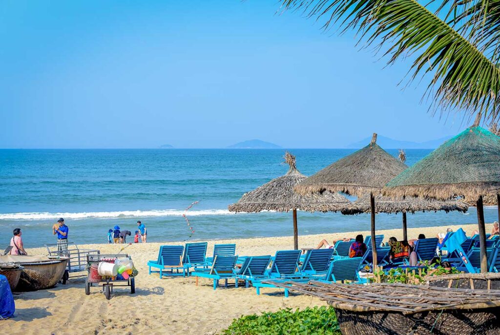 Tourists relaxing at An Bang Beach near Hoi An in May, enjoying hot sunny weather and calm blue sea during the early summer dry season.