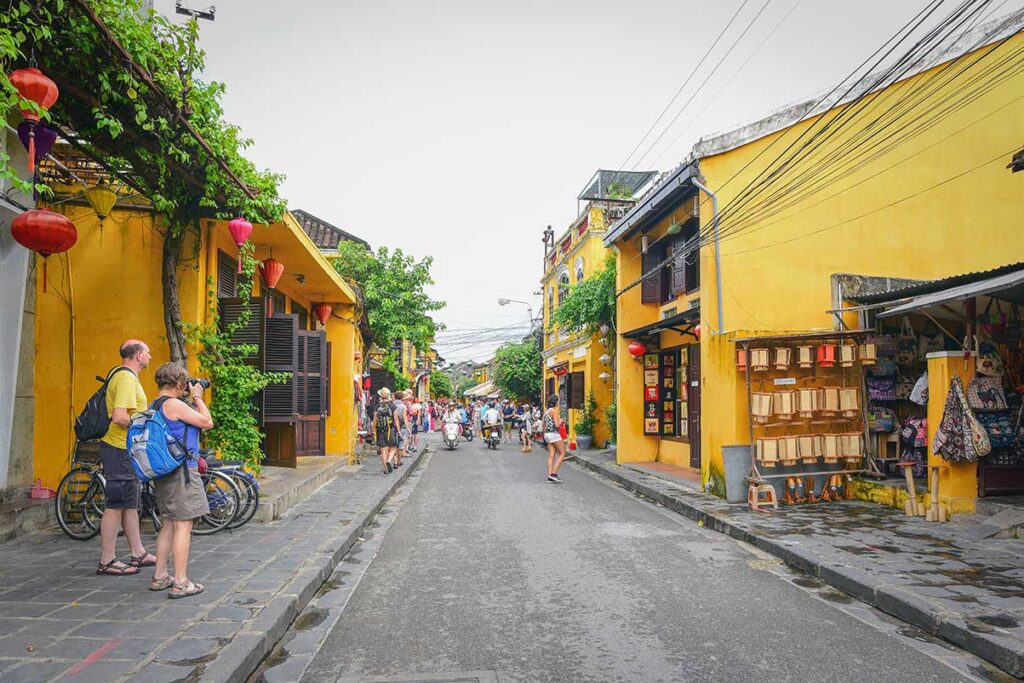 Tourists walking through Hoi An Ancient Town in November, when overcast skies and occasional drizzle create a cooler, quieter atmosphere for sightseeing.