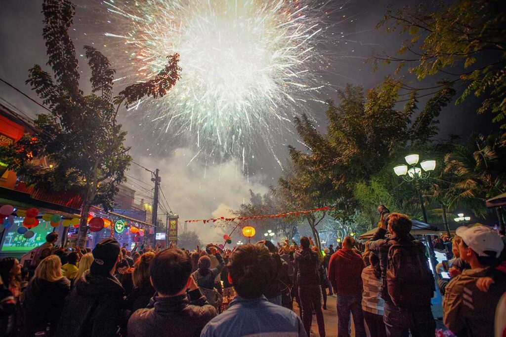 Crowds watching a colorful fireworks display in Hoi An during Tet, celebrating the Vietnamese Lunar New Year with music and street festivities.