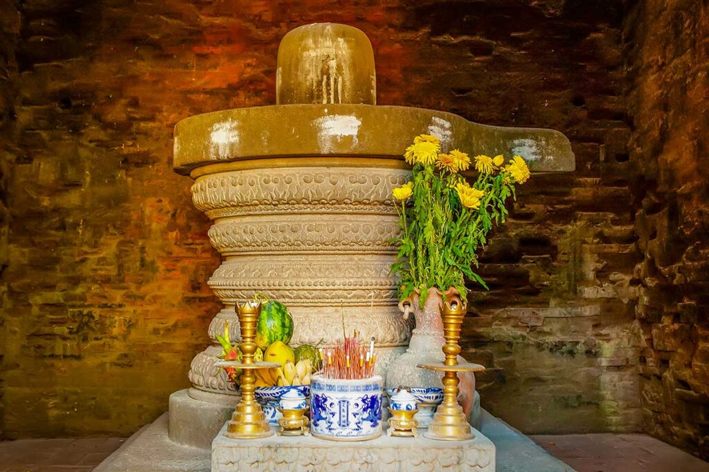 Cham Twin Towers Quy Nhon altar with Linga–Yoni – Stone shrine inside the tower with incense, offerings, and flowers, reflecting Cham Hindu worship traditions.
