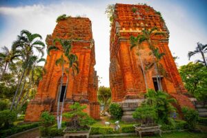 Cham Twin Towers at sunset light – Warm tones highlighting the historic red brick structures surrounded by tropical greenery.