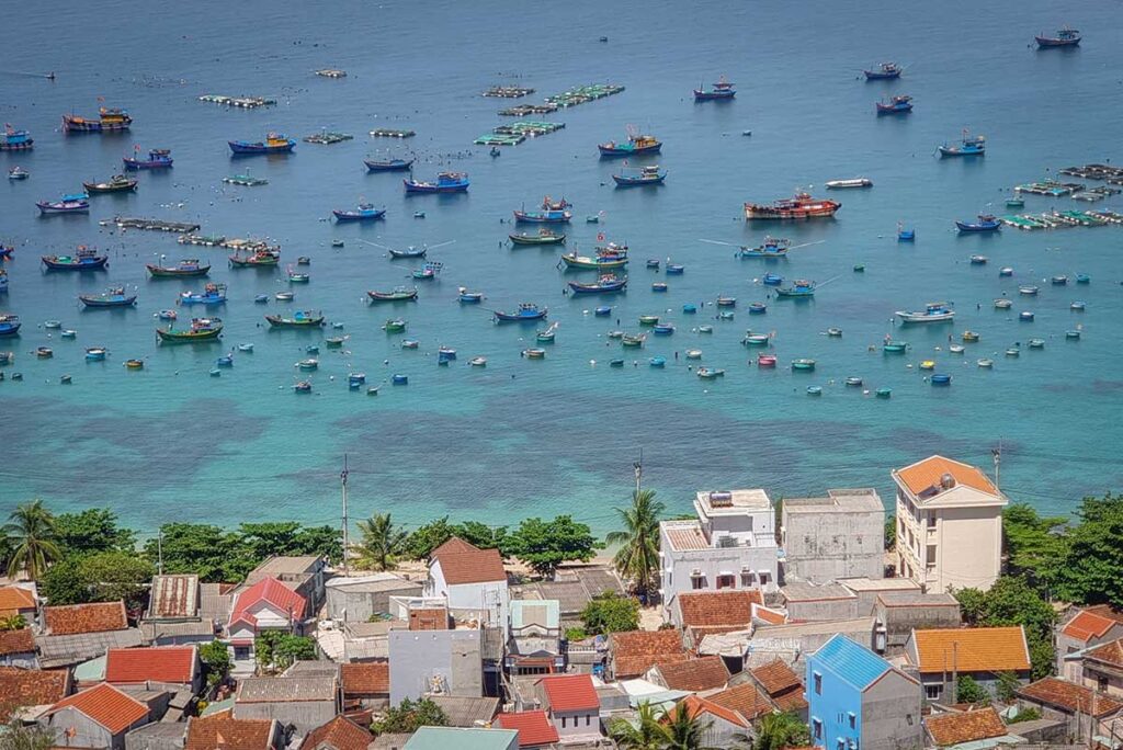 Colorful fishing boats and round basket boats anchored in the turquoise waters of Cu Lao Xanh fishing village, Quy Nhon.