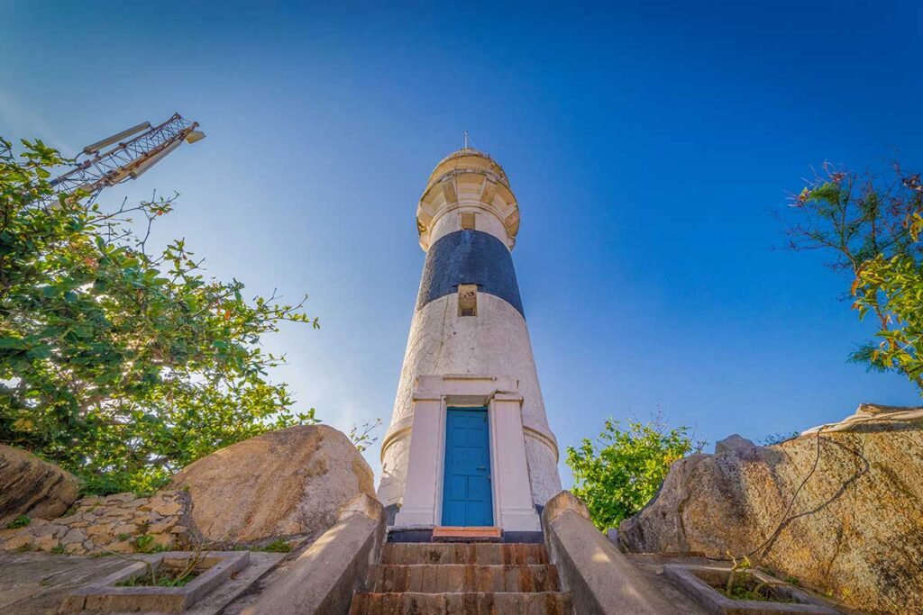 Historic Cu Lao Xanh Lighthouse, a black-and-white French-built structure overlooking the island and South China Sea.