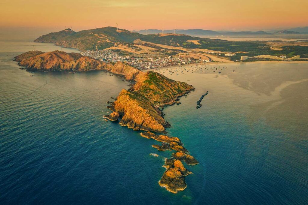 Drone view of the rocky Eo Gió headland stretching into the sea at sunset, Quy Nhon Vietnam