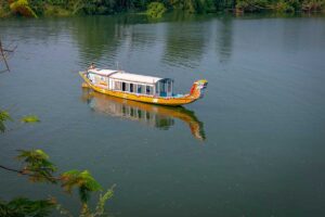 Traditional dragon boat cruising on the Perfume River in Hue, Vietnam, with peaceful green river views and lush riverside trees.