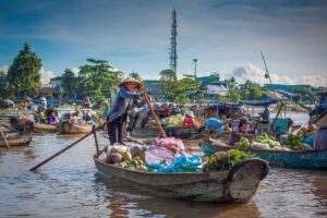 Produce-laden boats at a busy floating market at sunrise, highlighting hot late-dry-season mornings in the Mekong Delta in April.