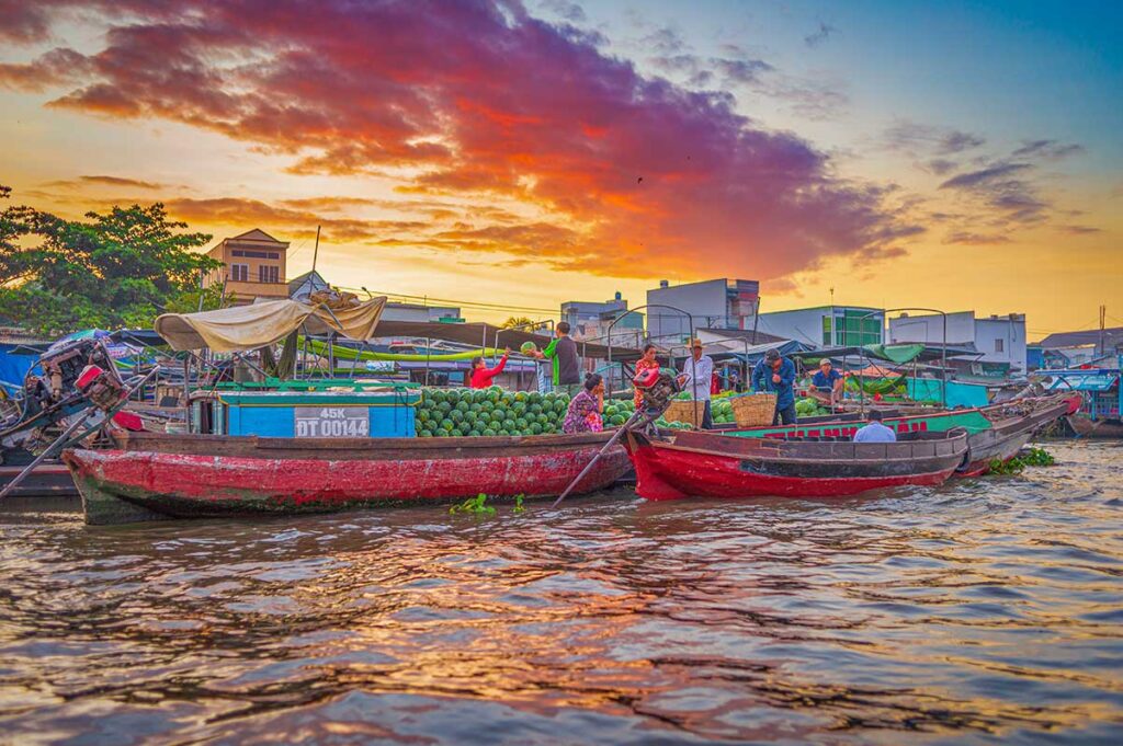 Boats loaded with watermelons at Cai Rang floating market during sunrise on a clear sky, showing a beautiful day in the Mekong Delta.