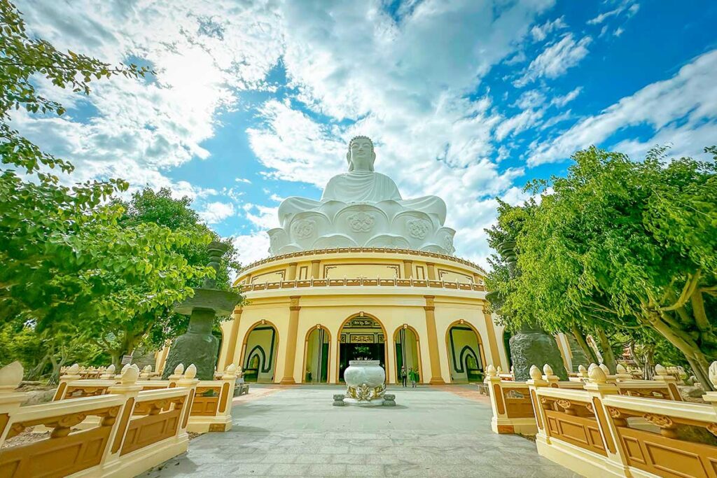 Front view of the white Buddha statue at Ong Nui Temple with temple gardens in the foreground.