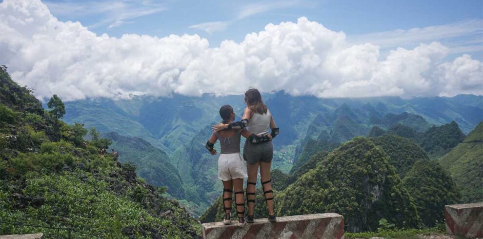 Two women in motorbike gear posing with mountain views during Ha Giang motorbike tour