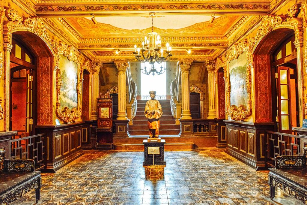 The entrance hall inside An Dinh Palace with a statue of Bao Dai