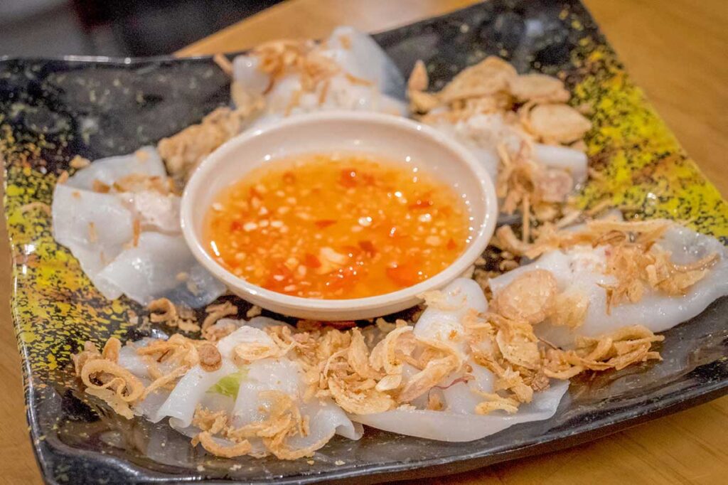 Delicate bánh bao bánh vạc, also called white rose dumplings, topped with crispy shallots and served with dipping fish sauce in Hoi An