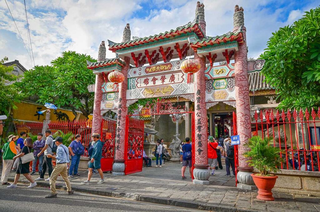 Street view of Cantonese Assembly Hall Hoi An with tourists entering through its decorated Chinese gate.