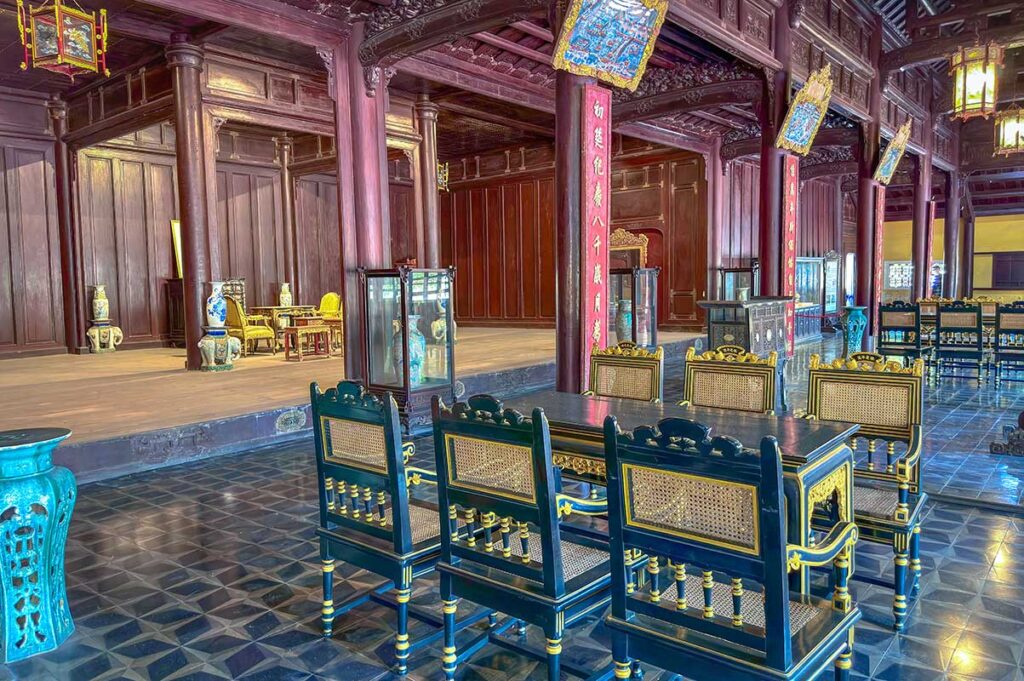 Inside Dien Tho Main Hall with antique chairs and ceramics and red wooden columns