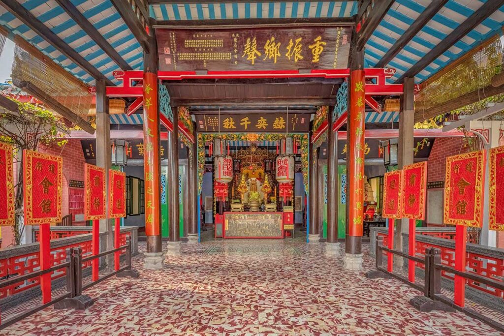Main worship hall of Hai Nam Assembly Hall Hoi An with ornate red and gold altar – cultural Chinese-Vietnamese heritage site dedicated to community and trade gods.