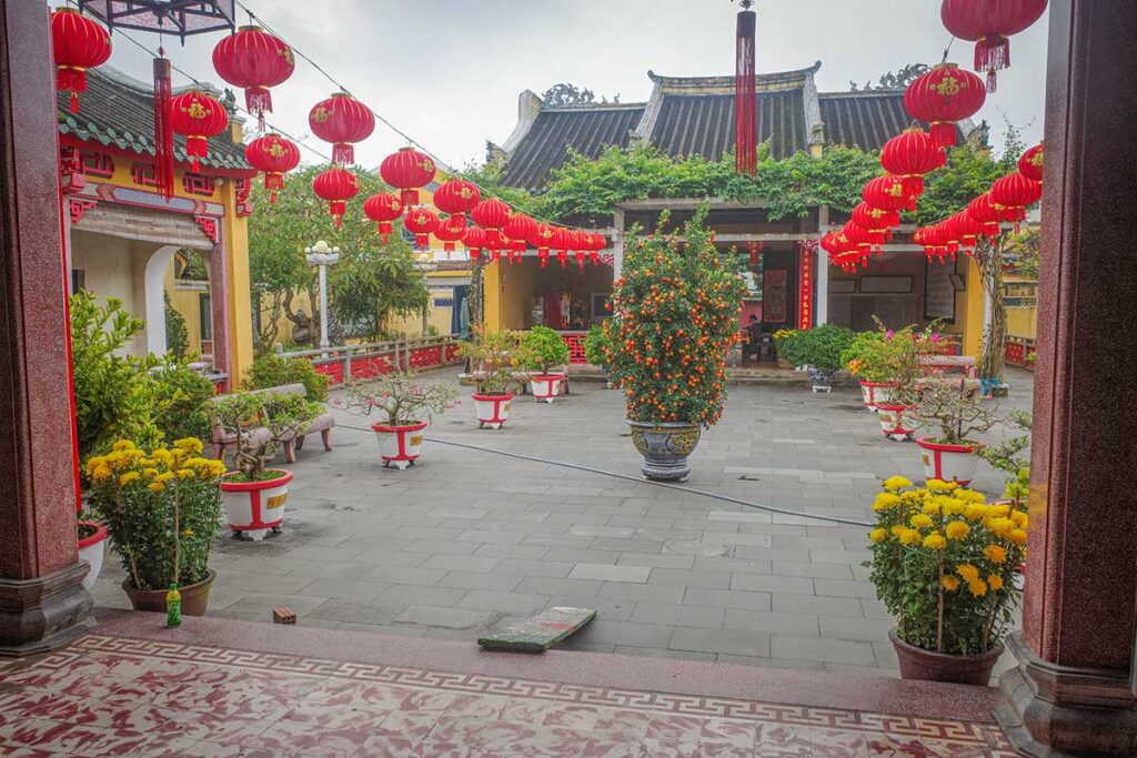 Courtyard of Hai Nam Assembly Hall decorated with red lanterns and bonsai trees, one of the best-preserved temples in Hoi An’s Ancient Town.