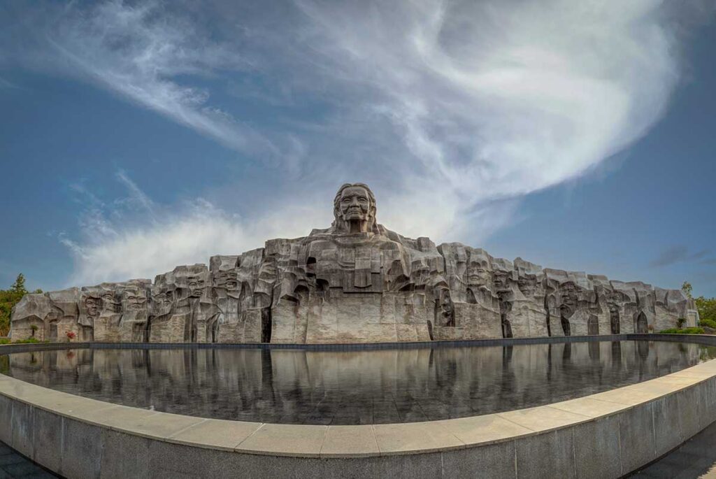 Massive Nguyen Thi Thu Heroic Mother Statue in Quang Nam, Vietnam, reflecting in a water pool.